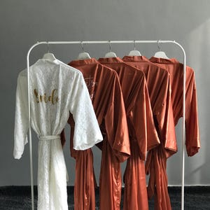 a collection of robes hanging on a rack, with a white robe prominently displayed in the foreground.
