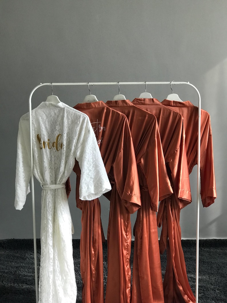 a collection of robes hanging on a rack, with a white robe prominently displayed in the foreground.
