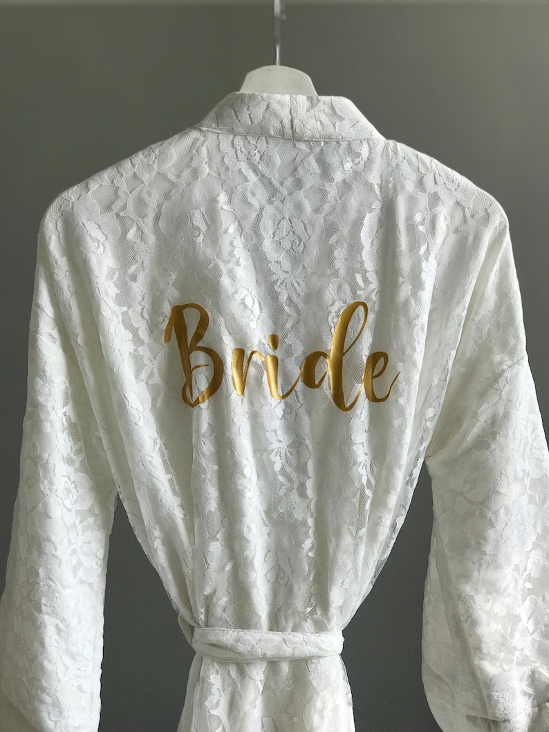 A white lace robe with the word "Bride" printed in gold on the back.