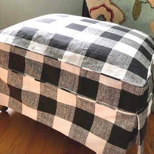 May include: Black and white checkered fabric ottoman with a pleated skirt. The ottoman is made of a soft, comfortable fabric and has a simple, classic design.