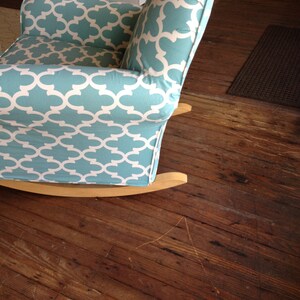 May include: A blue and white patterned rocking chair with a wooden frame. The chair is sitting on a wooden floor.