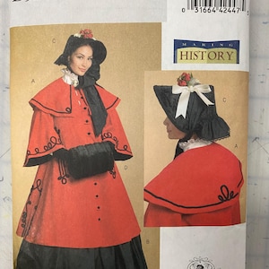 May include: Butterick B5266 sewing pattern for historical costumes. The pattern features a red coat and skirt with black trim, a black hat with floral accents, and a black scarf. The text "MAKING HISTORY" is visible.
