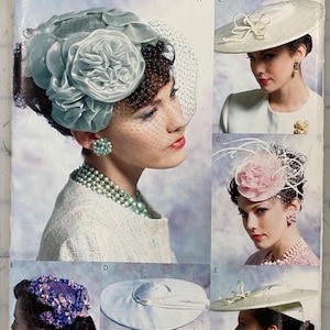 May include: Vogue accessories pattern V0652 featuring various women's hats. The hats include a blue floral headpiece with a veil, a white hat with a bow, a pink floral headpiece, a blue floral hat, and a white hat with a brim.