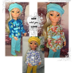 May include: Three dolls wearing vintage-style outfits. One doll wears a blue floral top and pants, another a floral top with a belt, and the third a daisy-print top and yellow pants. The image includes the text "Furga Atta Moda 'S' Doll" and "Sew what you love."
