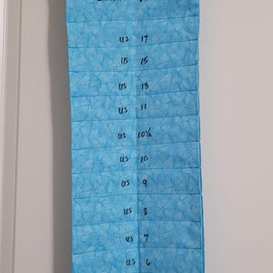 May include: A blue fabric organizer with a white hanger, labeled "Circular Needles" and listing US needle sizes from 2 to 17.