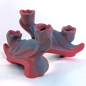 May include: A three-armed ceramic candlestick with a pink and blue glaze. The candlestick is shaped like stylized tulips.