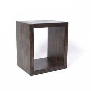 May include: A dark brown wooden cube shelf with a single open shelf. The shelf is made of solid wood with a natural wood grain.