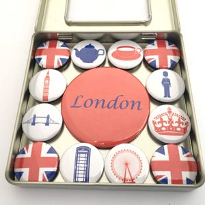 Puede incluir: Un conjunto de 12 imanes con tem&aacute;tica de Londres en una lata de plata. Los imanes presentan monumentos y s&iacute;mbolos ic&oacute;nicos de Londres, como la bandera de la Union Jack, el Big Ben, un autob&uacute;s de dos pisos rojo, una cabina telef&oacute;nica roja y el London Eye.