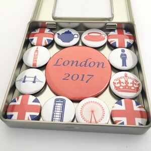 Puede incluir: Un conjunto de 12 pines redondos de esmalte rojo, blanco y azul en una lata de plata. Los pines presentan varios monumentos y s&iacute;mbolos de Londres, incluyendo la Union Jack, un autob&uacute;s de dos pisos rojo, una cabina telef&oacute;nica roja, Big Ben, el London Eye y la corona. La lata tiene el texto "London 2017" impreso en la parte delantera.