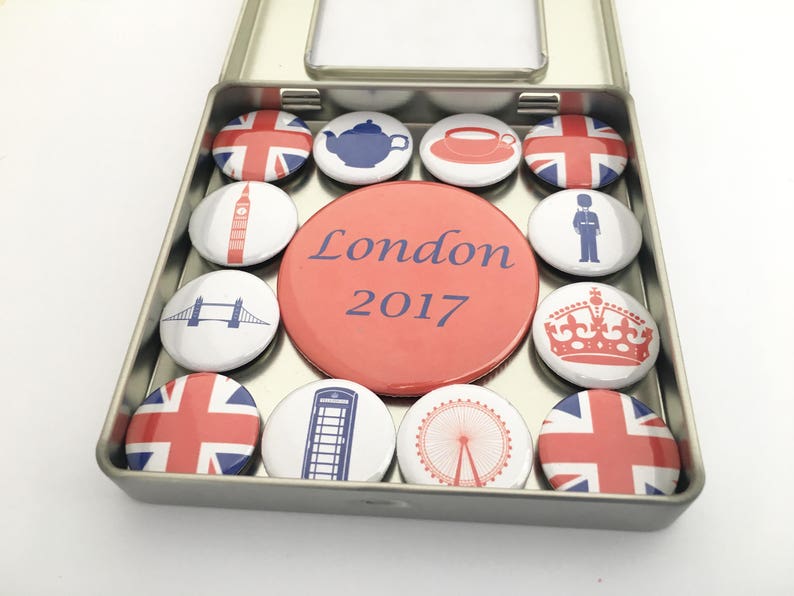 Puede incluir: Un conjunto de 12 pines redondos de esmalte rojo, blanco y azul en una lata de plata. Los pines presentan varios monumentos y s&iacute;mbolos de Londres, incluyendo la Union Jack, un autob&uacute;s de dos pisos rojo, una cabina telef&oacute;nica roja, Big Ben, el London Eye y la corona. La lata tiene el texto "London 2017" impreso en la parte delantera.