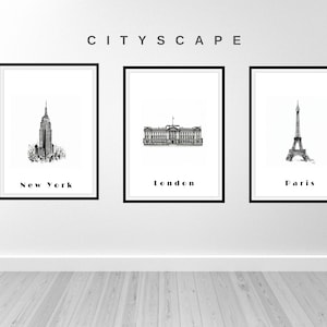 May include: Three black and white framed prints of cityscapes. The first print shows the Empire State Building with the text "New York". The second print shows Buckingham Palace with the text "London". The third print shows the Eiffel Tower with the text "Paris".