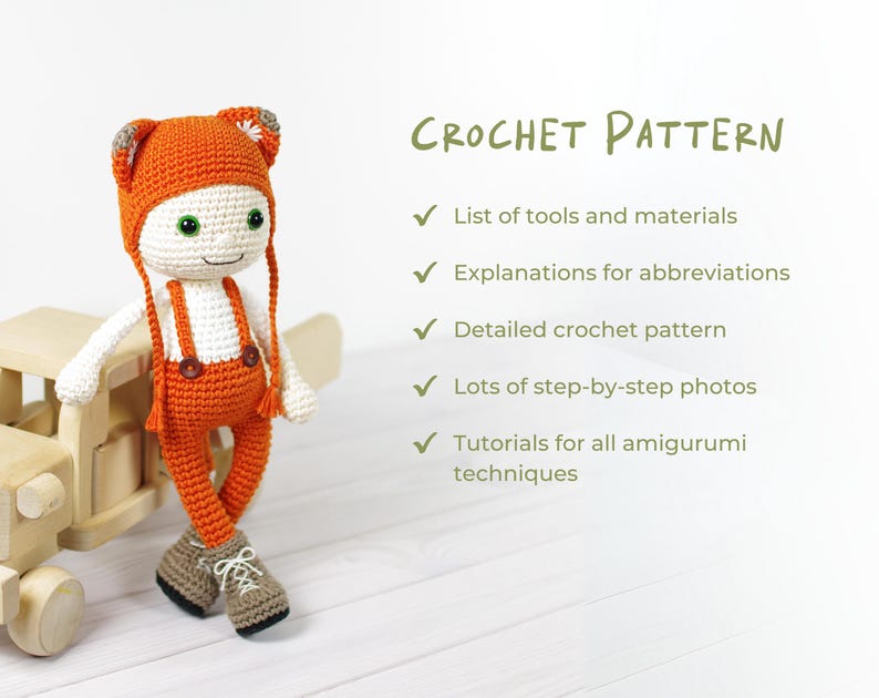May include: A crocheted amigurumi doll wearing orange overalls and a matching hat. The doll is standing on a wooden toy airplane. The image includes the text "CROCHET PATTERN" and a list of features included in the pattern.