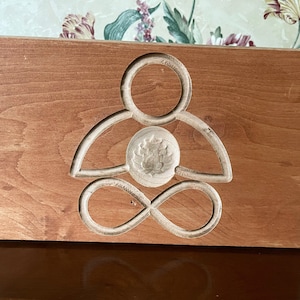 Meditating figure with Infinity symbol legs and Lotus carving at heart chakra