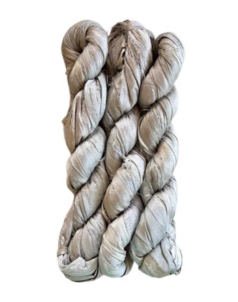 May include: A bundle of light taupe silk ribbon yarn featuring a crinkled, textured surface. The material is wound into a long, thick skein with visible frayed edges and a soft, matte sheen, displaying a consistent neutral color throughout.