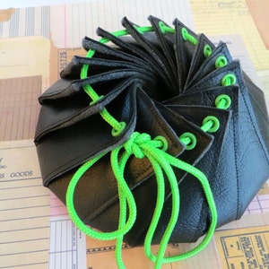 Może przedstawiać: Czarna skórzana torba ze sznurkiem do ściągania w kolorze zielonym. Torba jest zamknięta, a sznurek jest zawiązany.