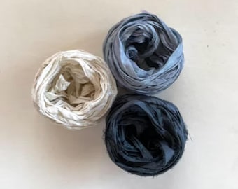 Könnte beinhalten: Drei Spulen Seidenband in den Farben Blau, Weiß und Schwarz. Das Band ist aus dünnem, zartem Stoff und eignet sich perfekt zum Basteln oder Dekorieren.