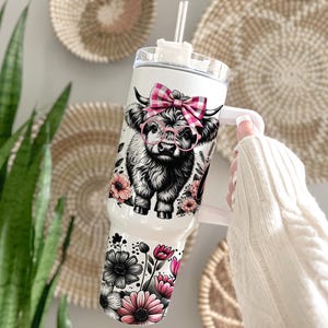 May include: White stainless steel tumbler with a black and white highland cow wearing pink glasses and a pink and white gingham bow. The tumbler is surrounded by pink and black flowers.