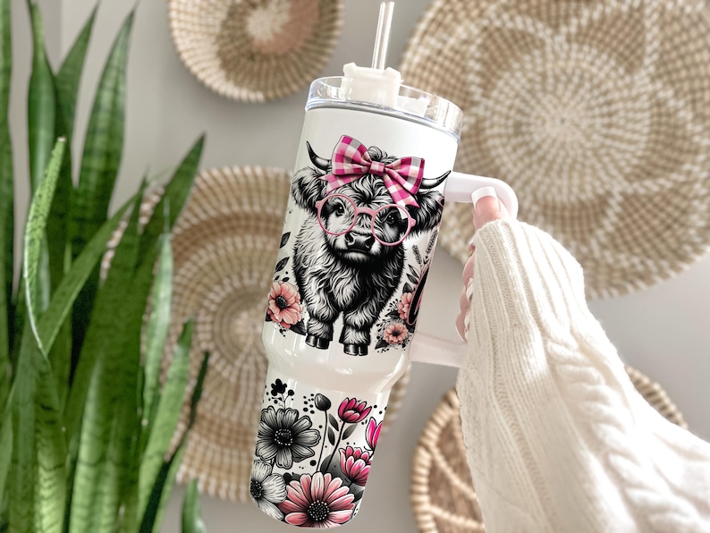 May include: White stainless steel tumbler with a black and white highland cow wearing pink glasses and a pink and white gingham bow. The tumbler is surrounded by pink and black flowers.