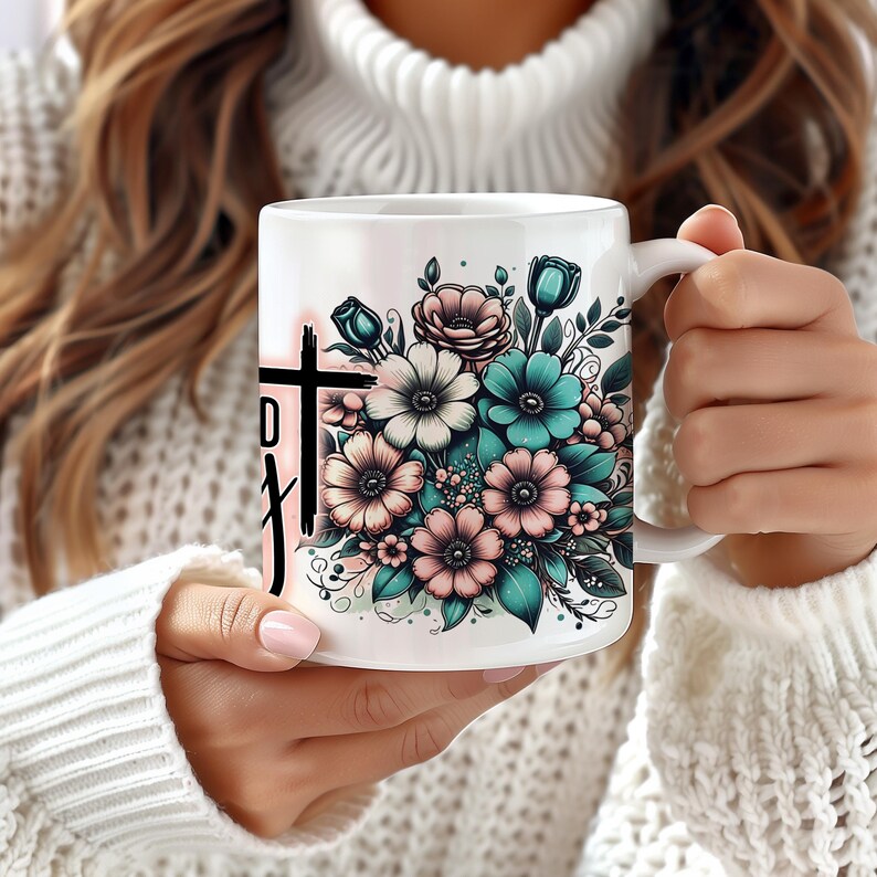 May include: White ceramic mug with a floral design featuring pink, white, and teal flowers. The mug has a black cross with the word "Faith" written on it.