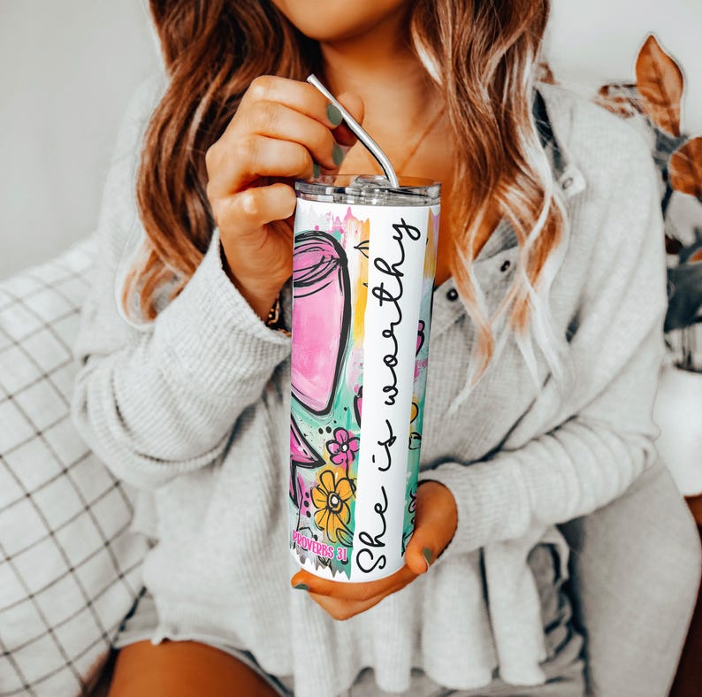 May include: A stainless steel tumbler with a colorful floral and jar design. The tumbler has the text "She is worthy" in a vertical stripe. The tumbler includes a silver straw.
