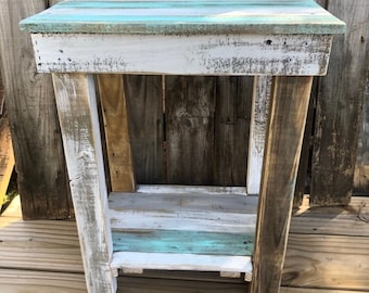 May include: A rustic wooden side table with a distressed white and blue paint finish. The table has a single shelf and is made from reclaimed wood.