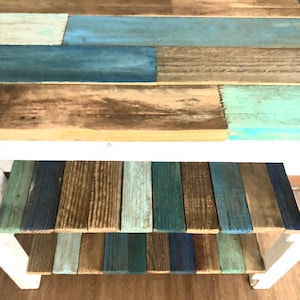 May include: A wooden shelf unit with two shelves. The top shelf is painted in shades of blue and brown, while the bottom shelf is painted in shades of blue, green, and brown.