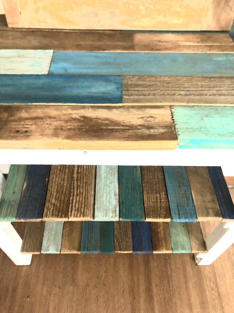 May include: A wooden shelf unit with two shelves. The top shelf is painted in shades of blue and brown, while the bottom shelf is painted in shades of blue, green, and brown.