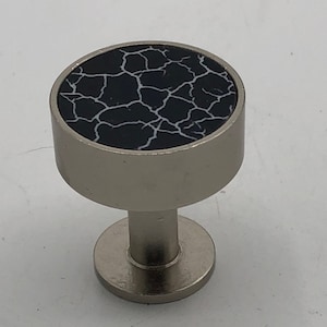 May include: A silver knob with a black and white cracked marble design.