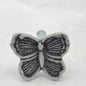 May include: Silver butterfly-shaped cabinet knob with a detailed design.