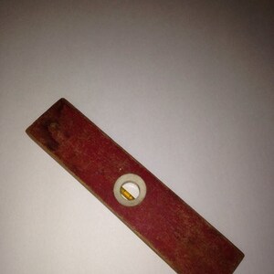 May include: A vintage wooden level with a red painted finish and a circular bubble level. The level is approximately 12 inches long.