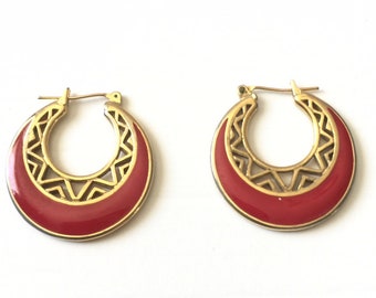 May include: A pair of gold hoop earrings with a red enamel design. The earrings have a geometric pattern and are a classic style.