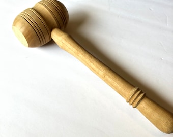 May include: A wooden meat mallet with a round head and a long handle. The head has a grooved design.