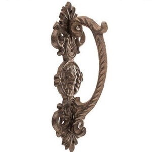 May include: Ornate cast iron door handle with a lion's head design and a decorative loop. The handle is a dark brown color and has a rustic finish.