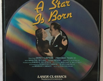 May include: A black and silver laser disc with a colour image of a couple dancing. The title "A Star Is Born" is printed in yellow on the disc. The disc is labelled "Laser Classics" and "Manufactured Exclusively by Image Entertainment".