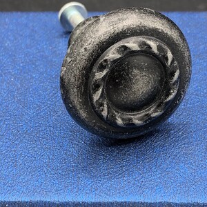 May include: Black metal cabinet knob with a decorative ring around the center. The knob has a distressed finish.