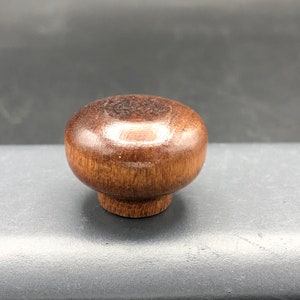 May include: A round wooden knob with a dark brown finish. The knob has a smooth, polished surface.