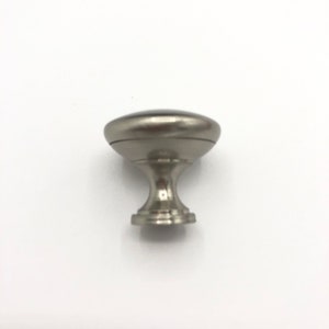 May include: A silver cabinet knob with a round top and a decorative base.