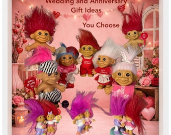 May include: A collection of various troll dolls with colorful hair, some wearing outfits, displayed against a pink background with the text Wedding and Anniversary Gift Ideas You Choose. The dolls feature distinct hair colors and clothing styles.