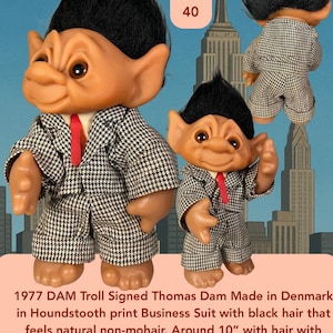 May include: Vintage 1977 DAM Troll doll, signed by Thomas Dam, wearing a houndstooth business suit with a red tie. The troll has black hair and is approximately 10 inches tall. The doll has posable arms and head.