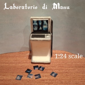 May include: A miniature X-ray machine in white and silver, with a screen showing medical images. The text "Laboratorio di Manu" is above, and "1:24 scale" below. Several small X-ray film images are scattered in front of the machine.