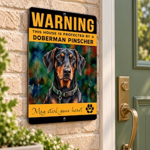 May include: A rectangular metal sign with a black and yellow border featuring the text WARNING THIS HOUSE IS PROTECTED BY A DOBERMAN PINSCHER and May steal your heart. The center displays a watercolor-style portrait of a Doberman Pinscher dog.