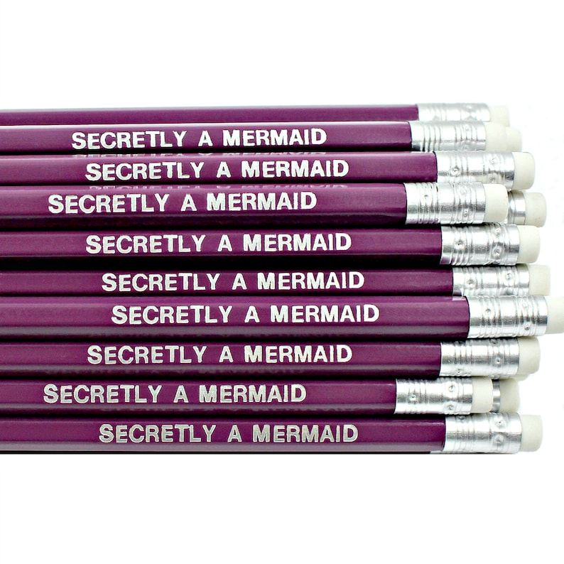 May include: A stack of ten purple pencils with silver accents and white erasers. Each pencil has the text "Secretly a Mermaid" printed in silver on the side.