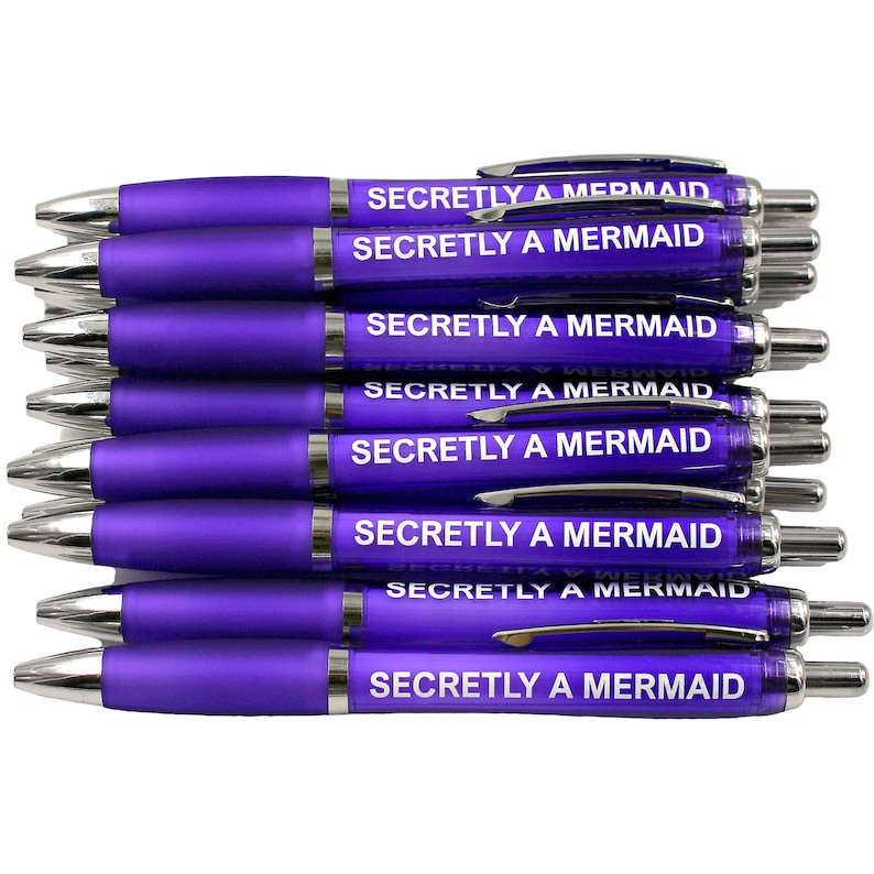 May include: A stack of ten purple pens with silver accents. Each pen has the text "Secretly a Mermaid" printed in white on the barrel.