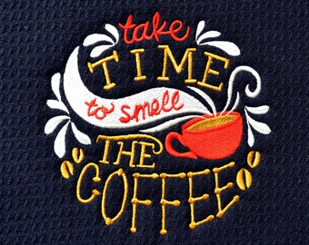 May include: Navy blue embroidered towel featuring the text "take TIME to smell THE COFFEE" in red and yellow thread. A red coffee cup and coffee beans are also embroidered. The text "The Jackson Inn" is embroidered at the bottom.