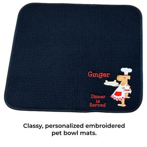 May include: Black pet bowl mat with red embroidered text that says "Ginger Dinner is Served" and a cartoon dog wearing a chef hat and holding a plate.