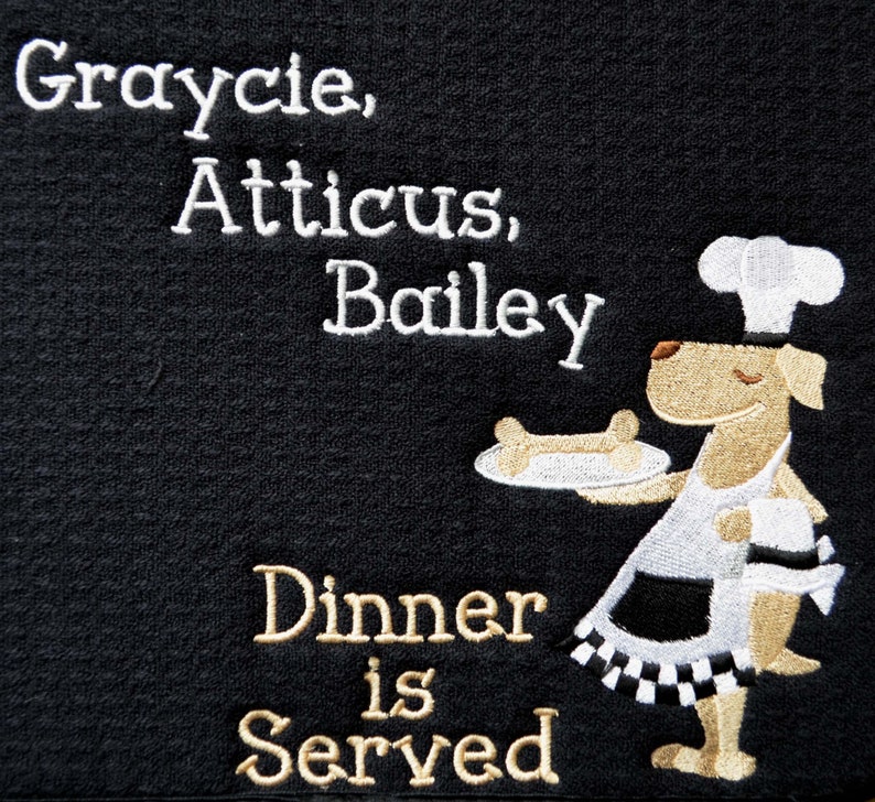 May include: Black doormat with white embroidered text that reads "Graycie, Atticus, Bailey Dinner is Served". A cartoon dog wearing a chef's hat and apron is holding a plate with a bone on it.