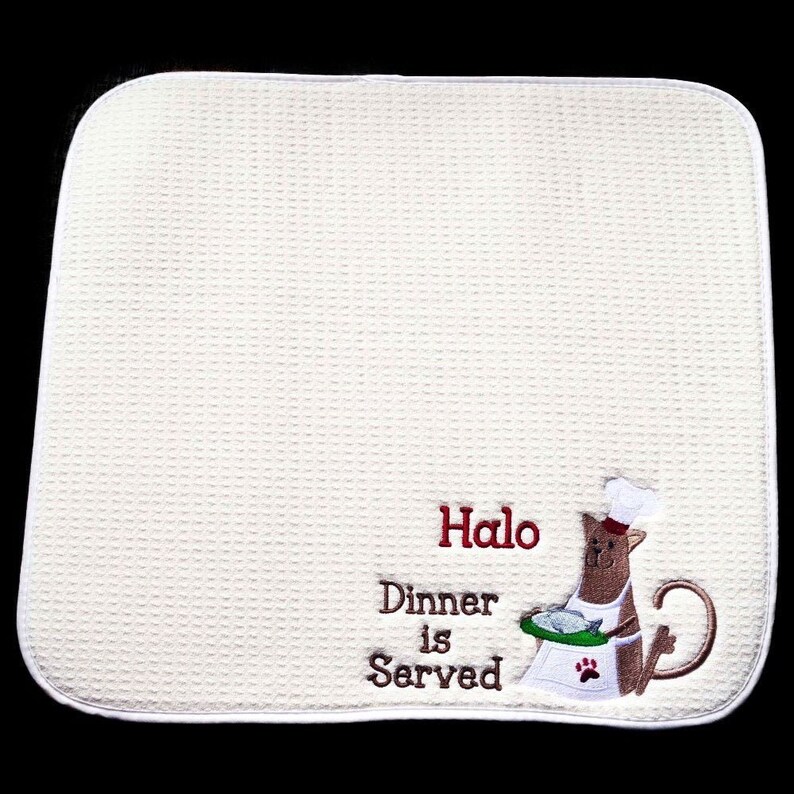 May include: White waffle weave kitchen towel with red embroidered text "Halo Dinner is Served" and a cartoon dog wearing a chef's hat holding a plate of fish.