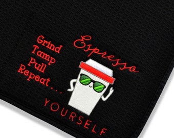 May include: A black textured mat featuring an embroidered white coffee cup character wearing green sunglasses and a red headband. The text reads: Espresso, Grind, Tamp, Pull, Repeat, and YOURSELF in red embroidery.
