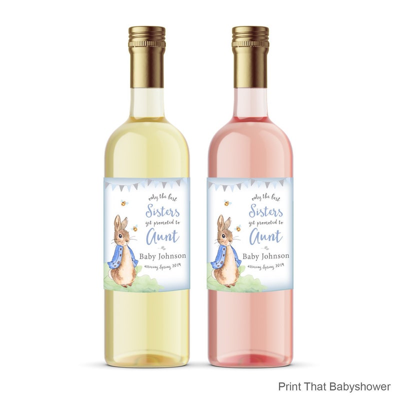 Puede incluir: Dos botellas de vino, una con l&iacute;quido amarillo claro y otra con l&iacute;quido rosa. Cada botella tiene una etiqueta con una ilustraci&oacute;n de un conejo con una chaqueta azul y el texto: "Only the best Sisters get promoted to Aunt."