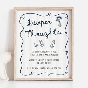 May include: A framed print with the words "Diaper Thoughts" in a whimsical font, surrounded by a navy blue border. The print includes illustrations of a pacifier, a bunny, and a baby bottle. Text encourages leaving a message for new parents.